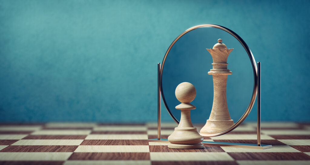 pawn chess piece looking in mirror and seeing queen chess piece