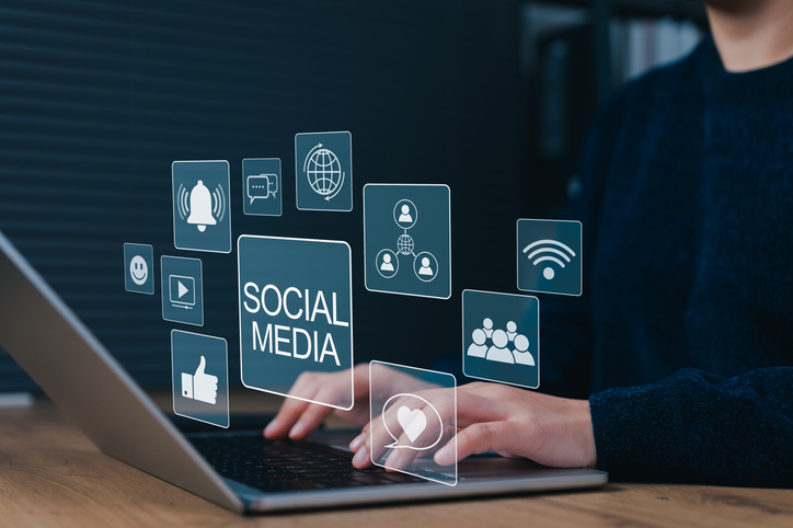 person typing on laptop with virtual icons for likes, notifications, comments, and other icons